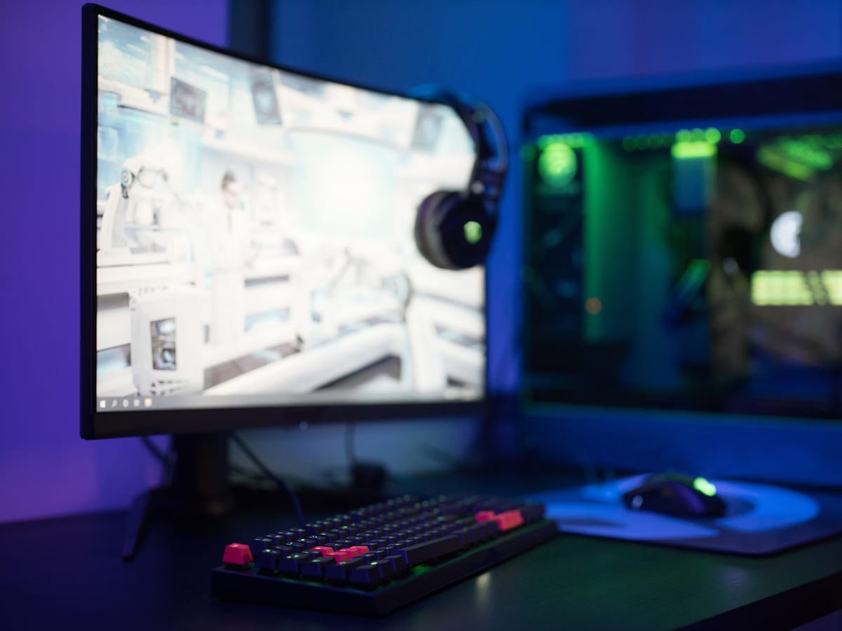 Puesto de juego con monitor, teclado retroiluminado, ratón y auriculares sobre una mesa